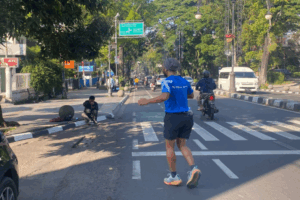 Street photographer mengambil foto pelari di Jalan Dago, Bandung. Sekarang pelari bisa mendapatkan hasil jepretan fotografer di aplikasi FotoYu.